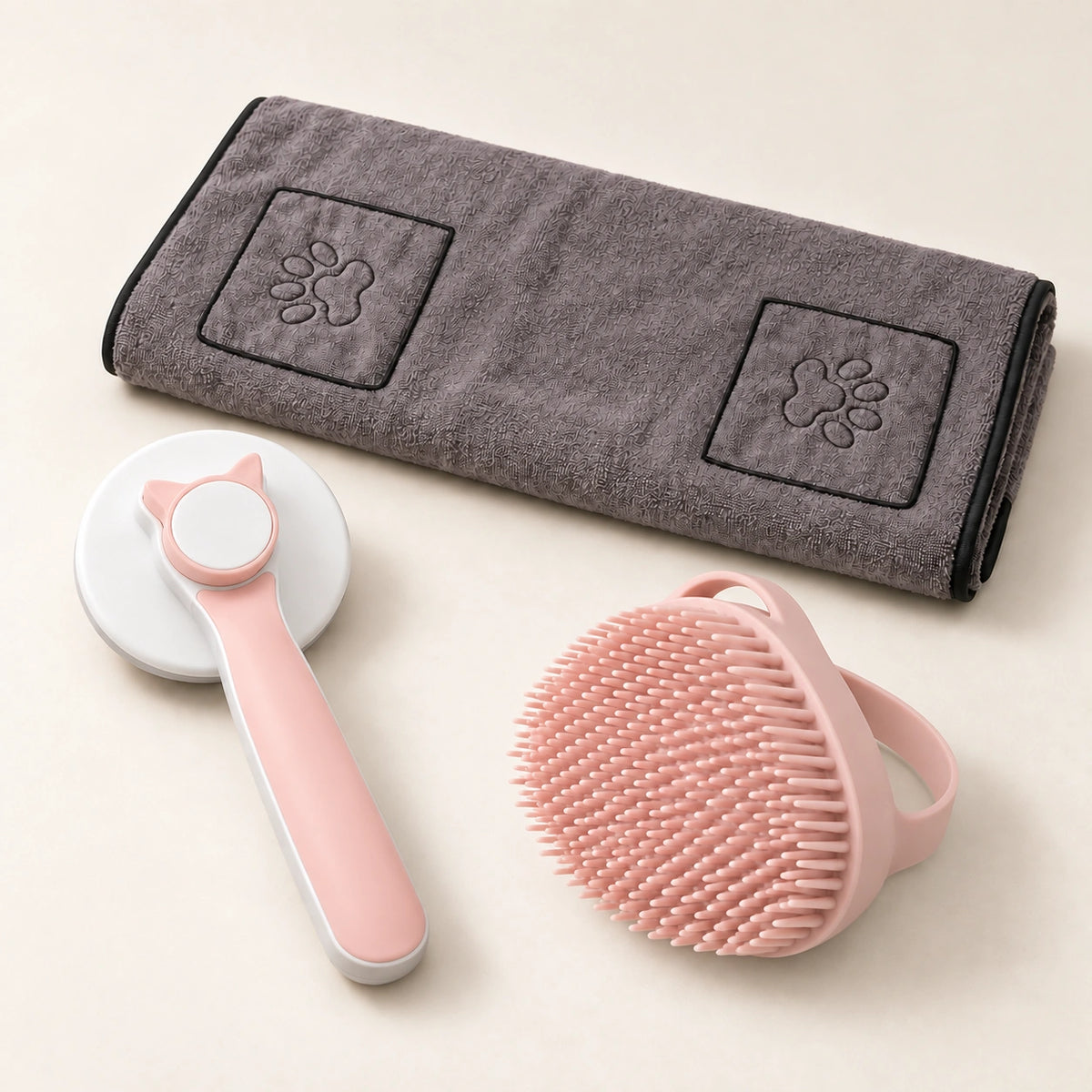 Pink grooming brush and bath brush beside a gray towel with two paw-detail hand pockets.