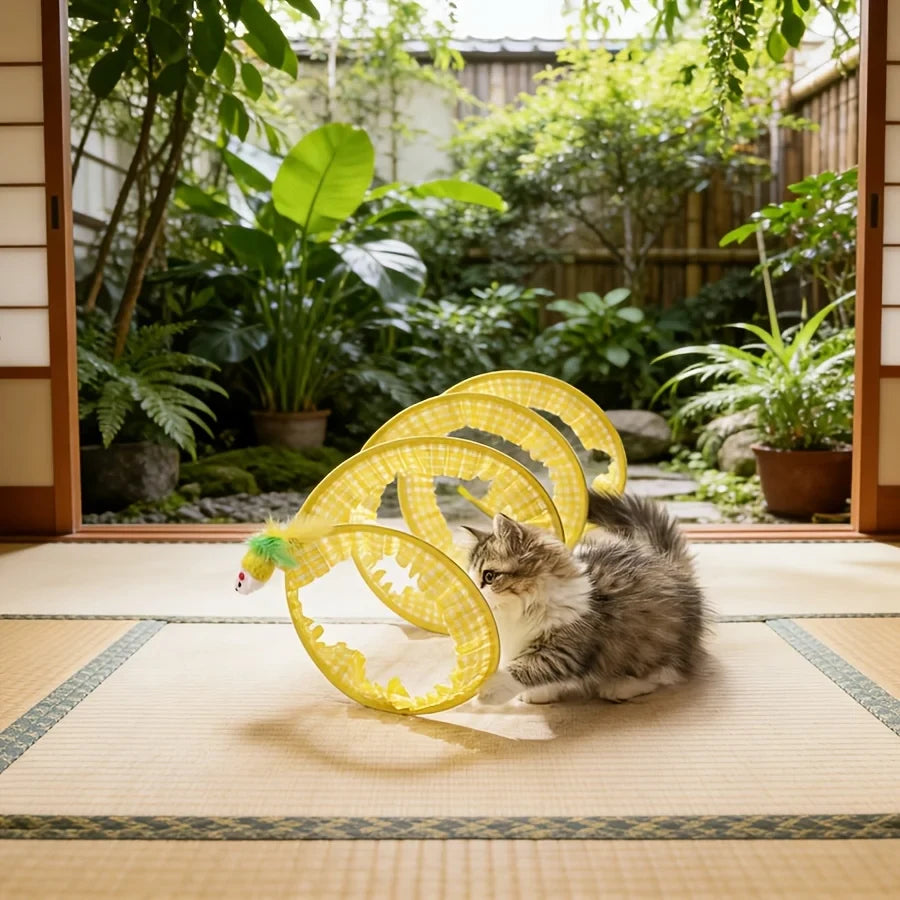 Cat playing inside a yellow collapsible spiral tunnel outdoors.