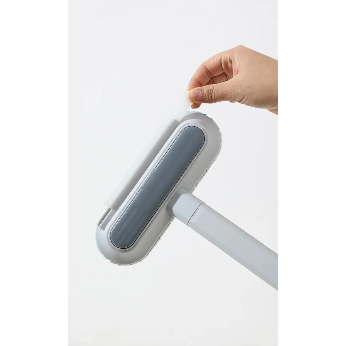 Hand removing the narrow brush from the slot in the gray head of the pet hair removal tool.