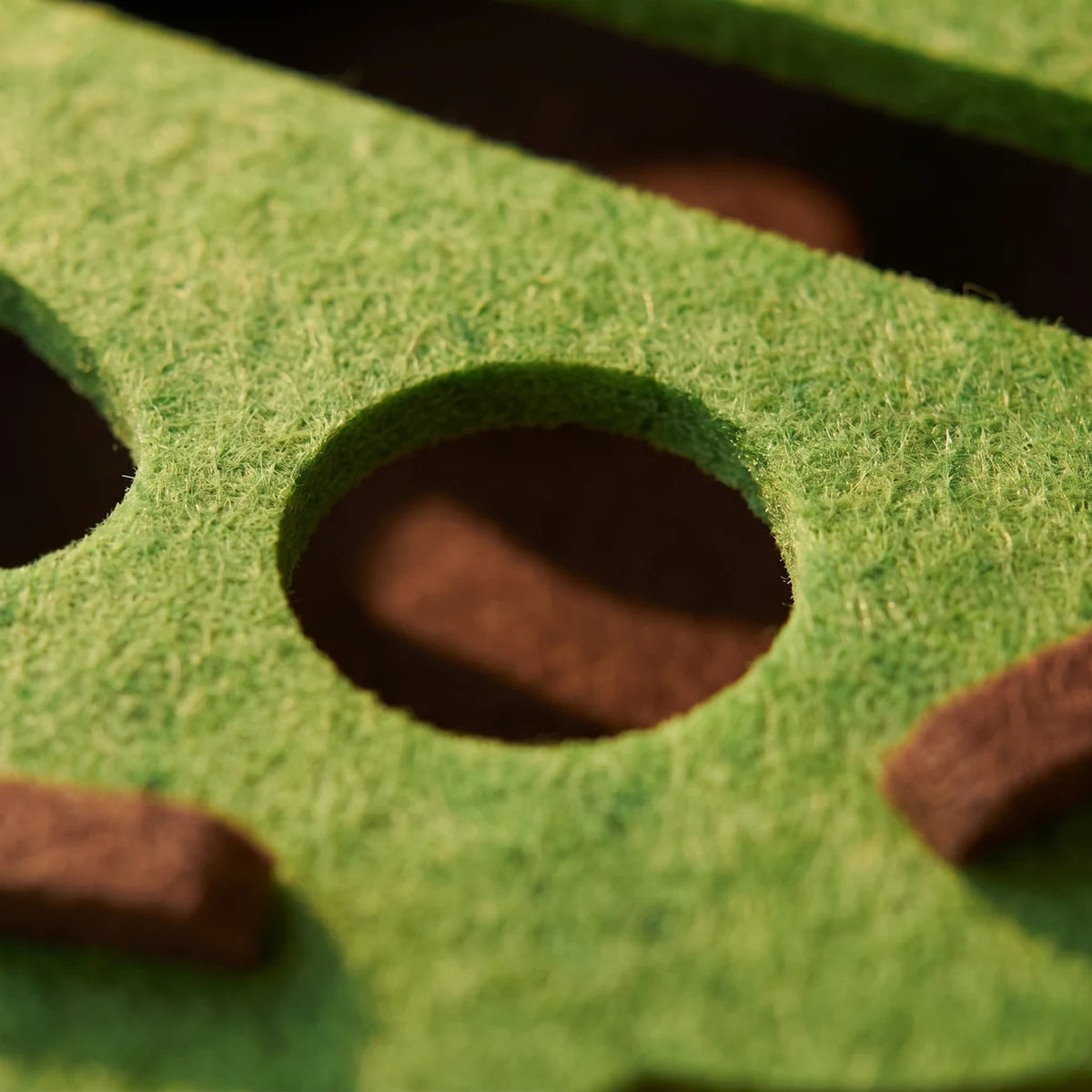Close-up of the green felt surface and rounded opening on the cat puzzle toy.