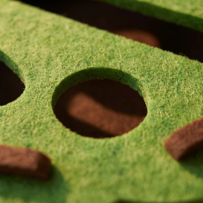 Close-up of the green felt surface and rounded opening on the cat puzzle toy.