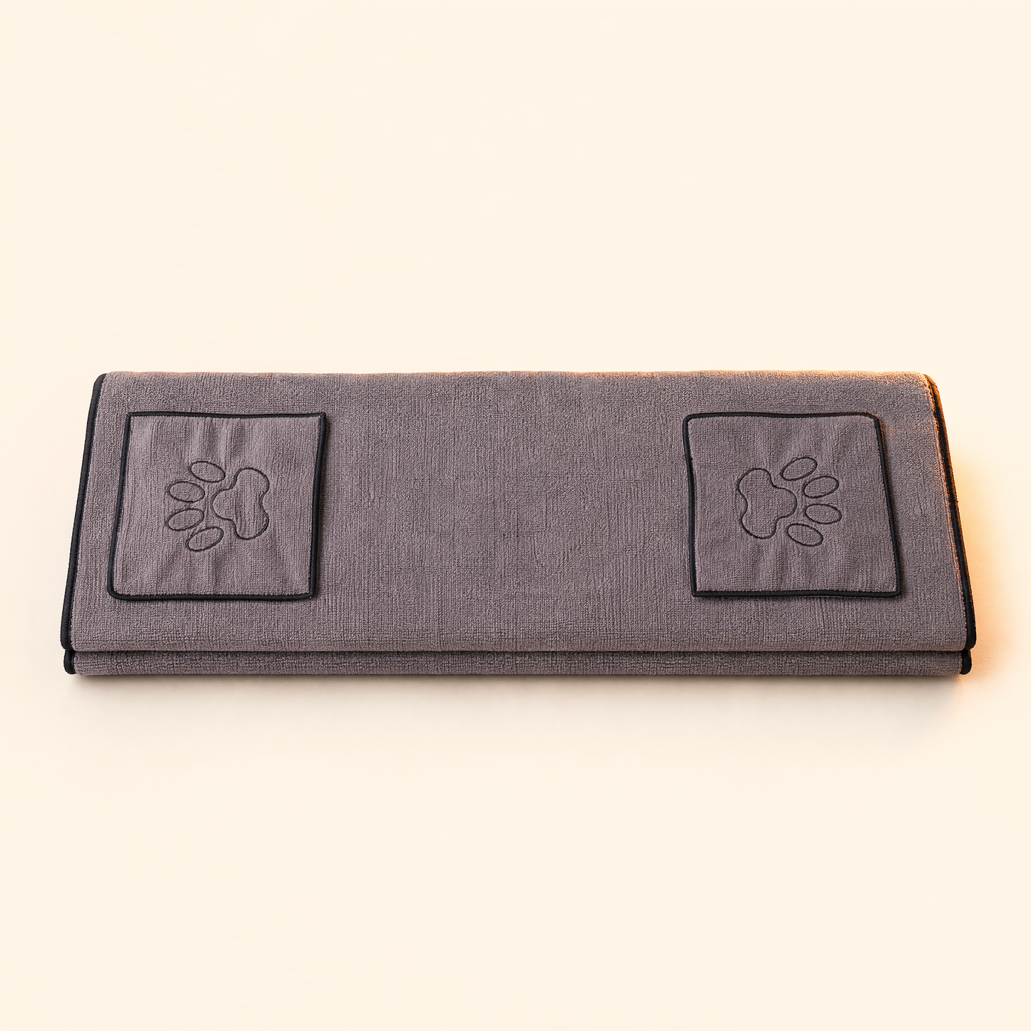 Grey pet drying towel with two paw-embroidered hand pockets on a soft cream background