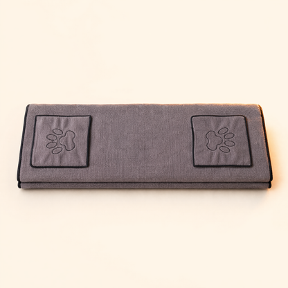 Grey pet drying towel with two paw-embroidered hand pockets on a soft cream background