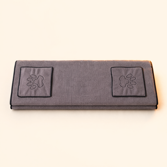 Grey pet drying towel with two paw-embroidered hand pockets on a soft cream background