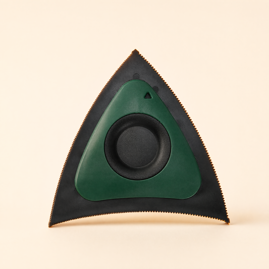 Green tri-edge pet hair scraper with black serrated edges on a soft cream background