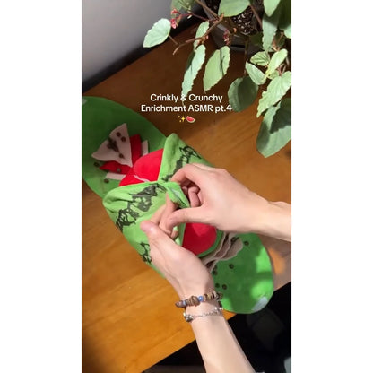 Hands opening the green watermelon-shaped plush toy to show its red inner sections.